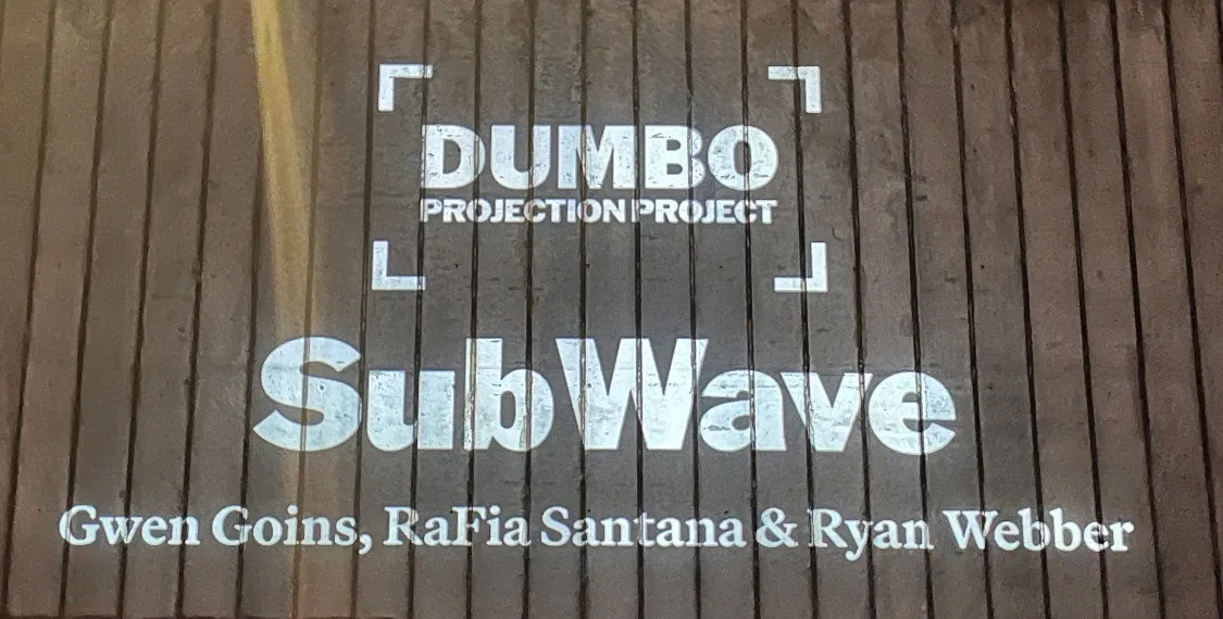 Projected title card crediting Gwen Goins, RaFia Santana, and Ryan Webber for SubWave at the Dumbo Projection Project